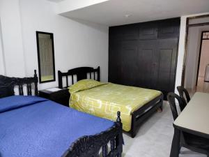 Un dormitorio con dos camas y una mesa y sillas. en Casita entre árboles, casa de huéspedes céntrica y cómoda en San Fernando, Cali, en Cali 2 fotos más