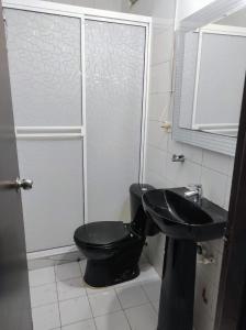 Un baño con un inodoro negro y un lavabo. en Casita entre árboles, casa de huéspedes céntrica y cómoda en San Fernando, Cali, en Cali
