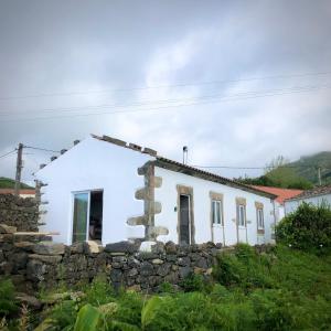 a white house with a stone wall at Casa Malagueta in Lajes das Flores
