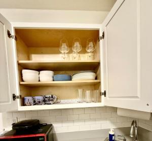 a kitchen cabinet with wine glasses and plates at NYCRiverside 2BR Apt 20MintsTime Square in West New York +16 photos