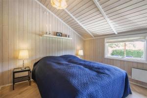 sypialnia z niebieskim łóżkiem i oknem w obiekcie SL256-Skaelskor-Ostre-Strand-115 w mieście Skælskør