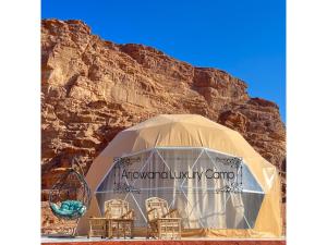 a tent with chairs in front of a mountain at Arjowana Luxury Camp in Wadi Rum