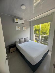 a bedroom with a white bed and a window at Disfruta y descansa en esta casa con Aire acondicionado in Ricaurte