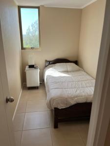 a small bedroom with a bed and a window at Villa Alemana Divertido in Villa Alemana