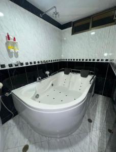 a large white tub in a bathroom with black tiles at Hotel Dream Luxury in Bogotá