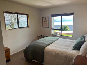 a bedroom with a bed and two windows at Atawhai Retreat Peace & Sea Views in Nelson