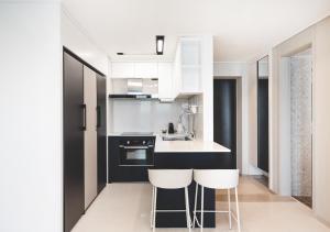 a kitchen with black and white counters and white appliances at Elmomento Songdo in Busan