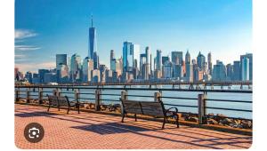 two benches on a pier with a view of a city at RiverEdge Apt Gateway20Mints FromTime SquareNYC in West New York