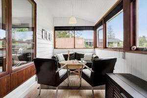 a dining room with a table and chairs and windows at 20221-Samso-Violvej-8 in Tanderup