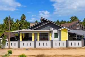a house with a yellow and white fence at D'Beris Homestay in Bachok
