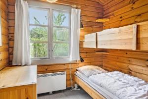 a bedroom with a bed and a window in a wooden wall at 20101-Samso-Gramejsevej-3 in Nordby