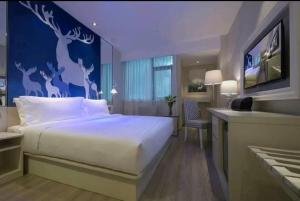 a bedroom with a large bed with deer painted on the wall at Orange Gu'an Beijing Daxing International Airport Hotel in Gu'an