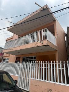 a pink house with a white fence in front of it at Departamento completo bien ubicado in Minatitlán