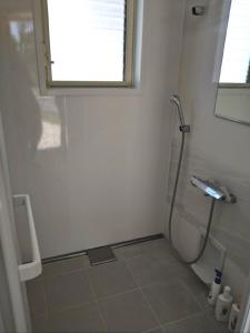 La salle de bains blanche est pourvue d'une douche et d'une fenêtre. dans l'établissement LaVilla - Vacation STAY 27368v, à Nobotate