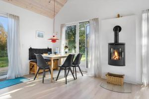 een eetkamer met een open haard en een tafel en stoelen bij 20142-Samso-Laerkevej-9-C in Nordby