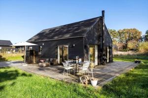 een zwarte schuur met een tafel en stoelen op een terras bij 20142-Samso-Laerkevej-9-C in Nordby