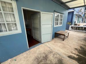 an open door to a blue house with a bench at Saen Saran property in Sathani Bang Ramat