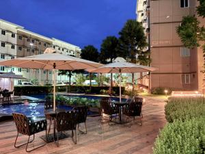 a patio with tables and umbrellas next to a pool at Gaelic Pure Place in Marilao