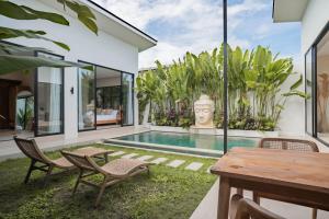 an outdoor patio with a table and chairs and a swimming pool at Lucky Villa 1 in Uluwatu