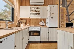 a kitchen with white cabinets and a white refrigerator at 20114-Samso-Blamejsevej-9 in Nordby