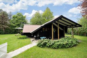 a black house with a red roof in a yard at 20114-Samso-Blamejsevej-9 in Nordby