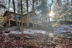 a log cabin in the woods with the sun shining at Gwen's Cottage at Water's Edge in Portersville