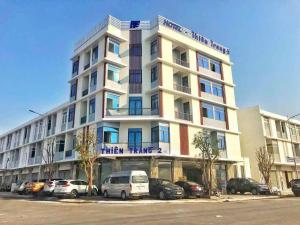 een hoog wit gebouw met auto's geparkeerd voor het bij Thiên Trang 2 Hotel - Khách sạn gần bến tàu Rạch Giá in Rach Gia