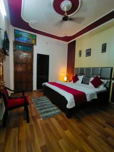 リシケーシュにあるShriJi Homestayのベッドルーム1室(大型ベッド1台、赤い椅子付)
