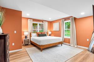 1 dormitorio con paredes de color naranja, 1 cama y ventana en The Respite getaway, en Harrisburg