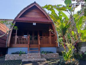 a small building with a porch in a garden at Kawandini Homestay in Sidemen