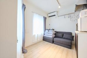 a living room with a couch and a window at 32 とりっぱーずホテル高田馬場 in Tokyo