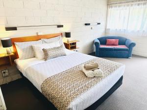 a bedroom with a large bed and a blue chair at Tartan Motel, Yea in Yea