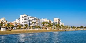 Una vista de una playa con edificios al fondo. en Modern 2BR Apartment 70m from Finikoudes beach, en Lárnaca