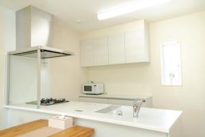 a white kitchen with a sink and a microwave at Villa NIRAI in Uruma
