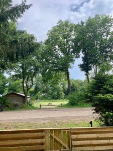 a wooden fence next to a dirt road with trees at Heerlijke ruime stacaravan met overdekte veranda en omheinde tuin ''Casa Elvina'' in Eext