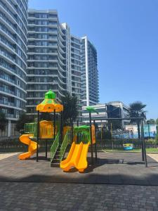 a playground with yellow and green equipment in a park at Квартира у моря с бассейном in Batumi