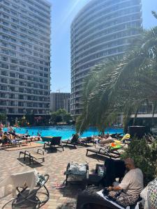 a group of people sitting in lawn chairs near a pool at Квартира у моря с бассейном in Batumi