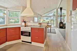 a kitchen with red cabinets and a stove top oven at 20311-Samso-Havvejen-87 in Sælvig