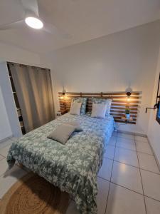 1 dormitorio con 1 cama con manta verde y almohadas en La Terrasse de Ugo, en Saint-Pierre
