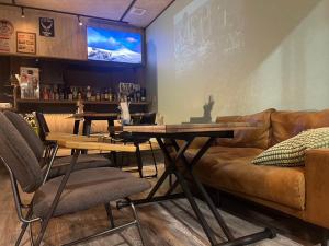 a bar with a couch and tables and a tv at Guesthouse NALUノ道 in Kobe