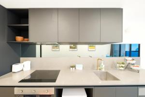 a kitchen with white cabinets and a sink at Easeful Canberra CBD 2BR Apt in Canberra +20 photos