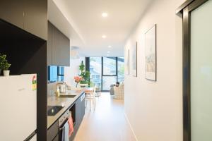 a kitchen with white walls and a white refrigerator at Easeful Canberra CBD 2BR Apt in Canberra