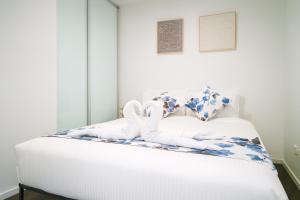 a white bed with two stuffed animals on it at Easeful Canberra CBD 2BR Apt in Canberra