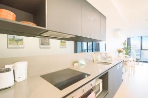 a kitchen with white cabinets and a counter top at Easeful Canberra CBD 2BR Apt in Canberra