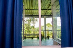 a room with a view of a balcony with blue curtains at 9 Arch view rest inn in Ella