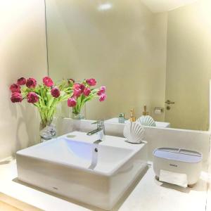a bathroom with a sink and a mirror and flowers at Oceanami Villas & Beach Club in Long Hai