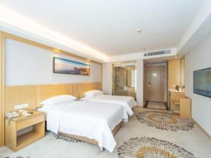 a hotel room with two beds and a television at Vienna Hotel Guangzhou Huadu Financial Center Sunac Amusement Park in Huadu