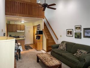 a living room with a green couch and a kitchen at Cozy Downtown Hunter Mountain Getaway in Hunter
