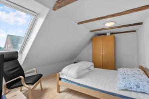 a bedroom with a bed and a chair and a window at AE219-Marstal-Ommelsvejen-14 in Marstal
