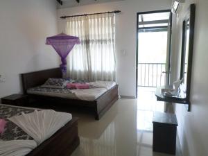 a bedroom with two beds and a window at Romana Rest Kataragama in Kataragama